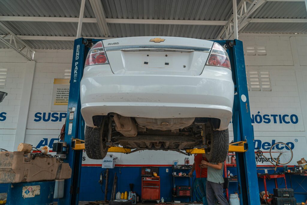 A white Chevrolet car is lifted for maintenance in an automotive repair shop.