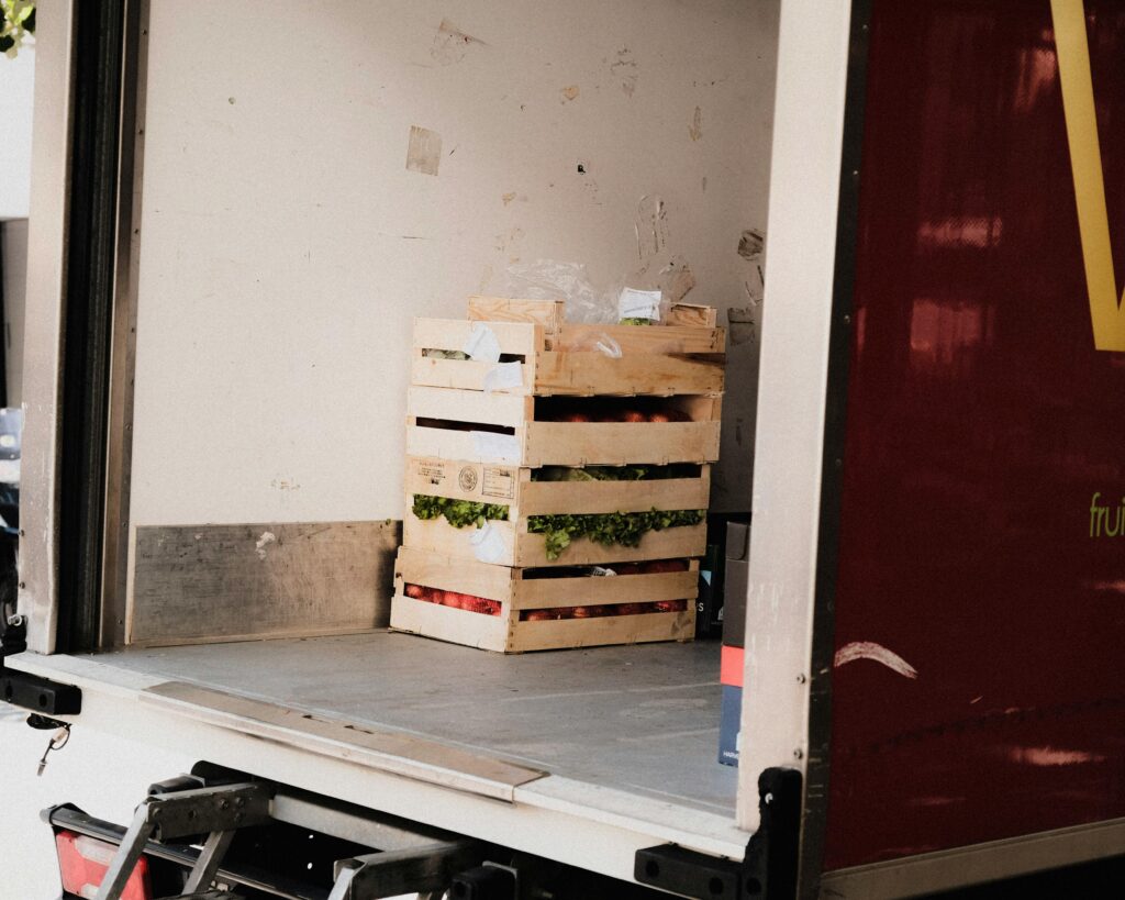 A wooden crate with fresh vegetables loaded inside a delivery truck, ready for transportation.