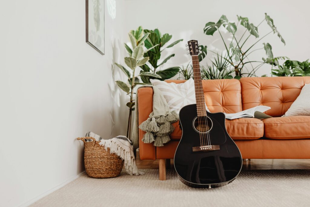 A stylishly decorated living room featuring a black acoustic guitar and lush house plants.